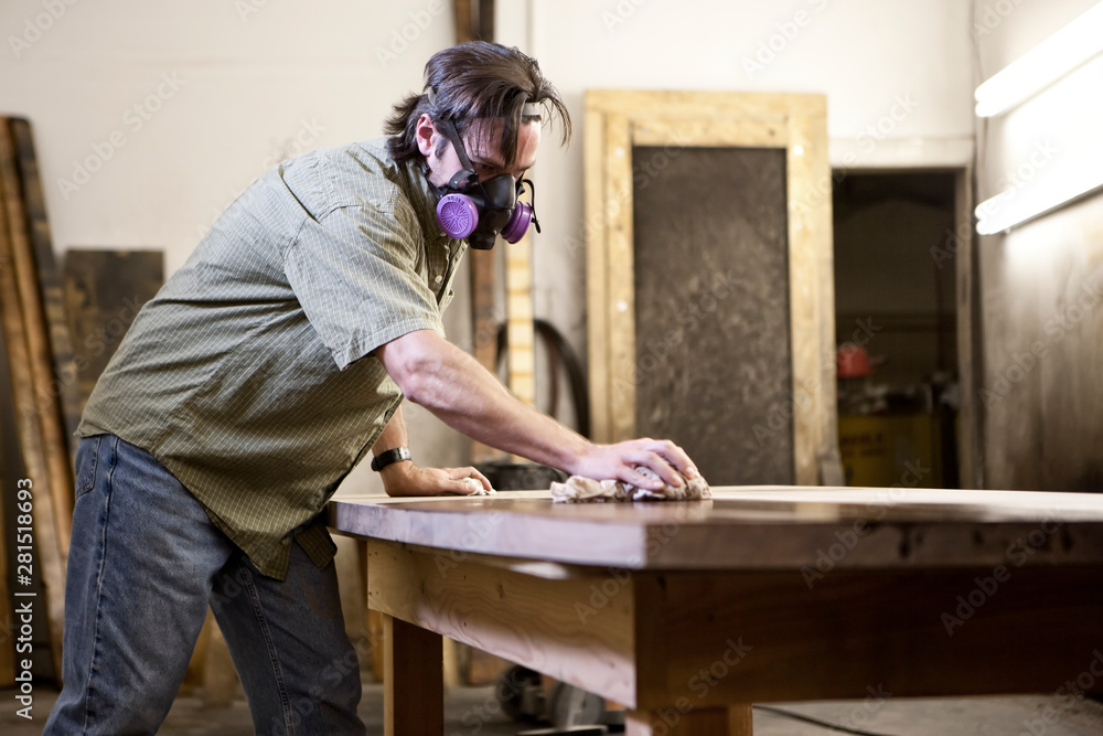 Factory worker applying finish stain on table in workshop Factory worker applying finish stain on table in workshop