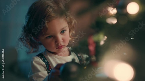 happy little girl decorating christmas tree with beautiful ornaments and baubles enjoying festive decorations at home on calm winter evening 4k footage