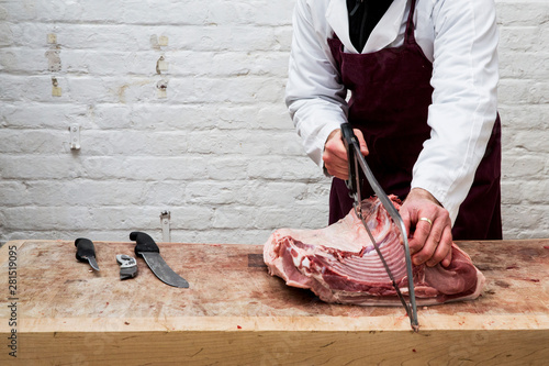 Midsection of butcher chopping piece of pork lion using saw