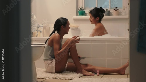 happy teenage sisters chatting in bathroom young girl bathing with sister sitting next to bath having conversation sharing gossip siblings enjoying quality time together at home 4k