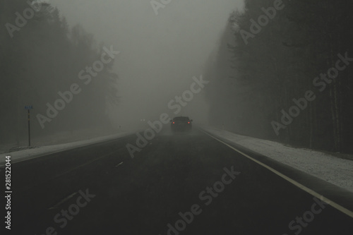 Car moving in snowstorm through the forest. car rides on a winter snowy road in cloudy weather