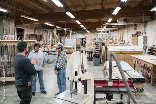 Carpenters talking with each other in workshop photo
