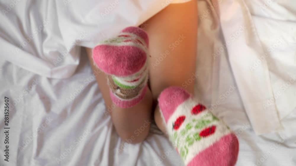 Top view. Beautiful female legs in bright multi-colored woolen socks move. Close-up. Top view. Beautiful female legs in bright multi-colored woolen socks move. Close-up.