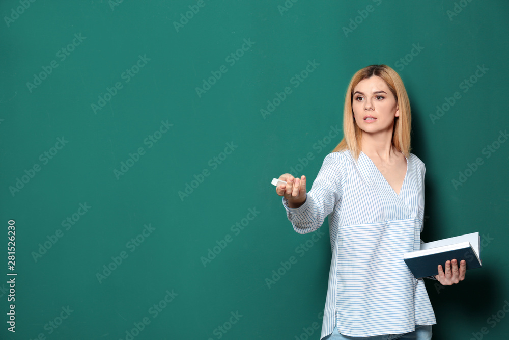 Beautiful teacher with book near chalkboard, space for text Beautiful teacher with book near chalkboard, space for text