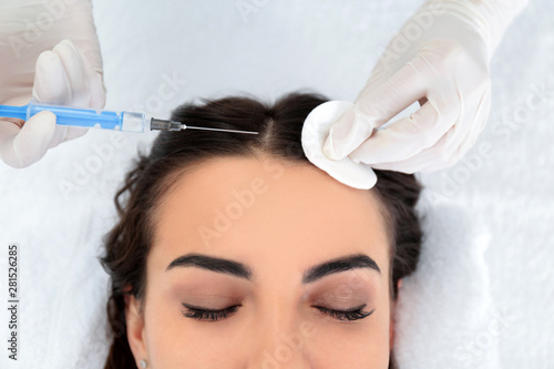 Young woman with hair loss problem receiving injection in salon, closeup