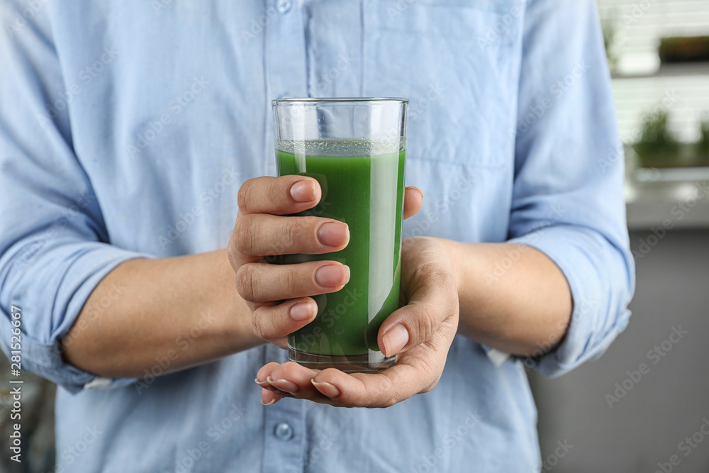Woman holding glass of wheat grass juice, closeup Woman holding glass of wheat grass juice, closeup