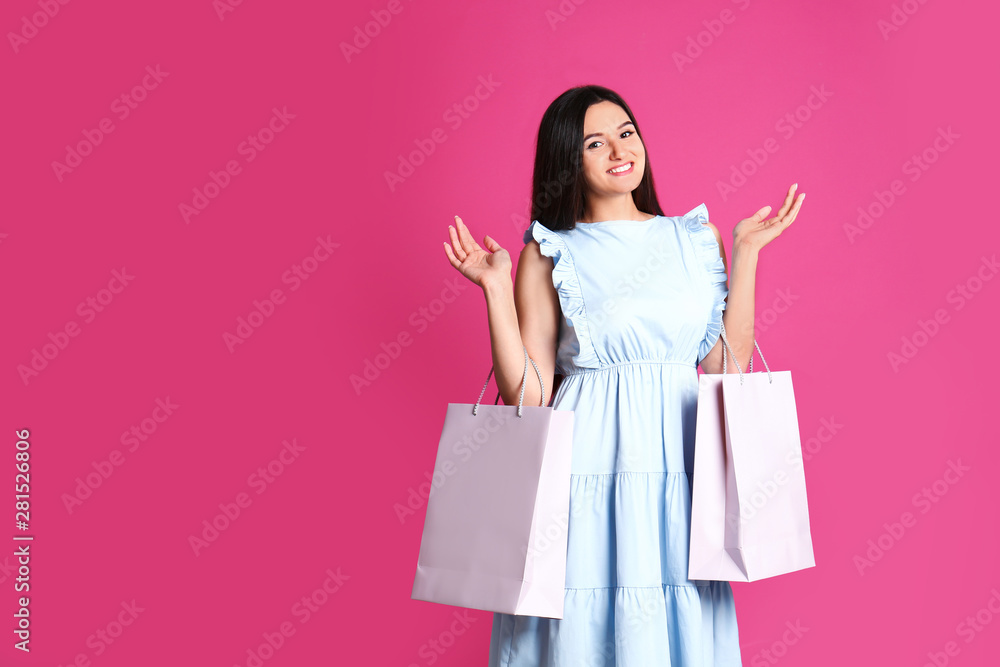 Beautiful young woman with blank paper bags against color background, space for text Beautiful young woman with blank paper bags against color background, space for text
