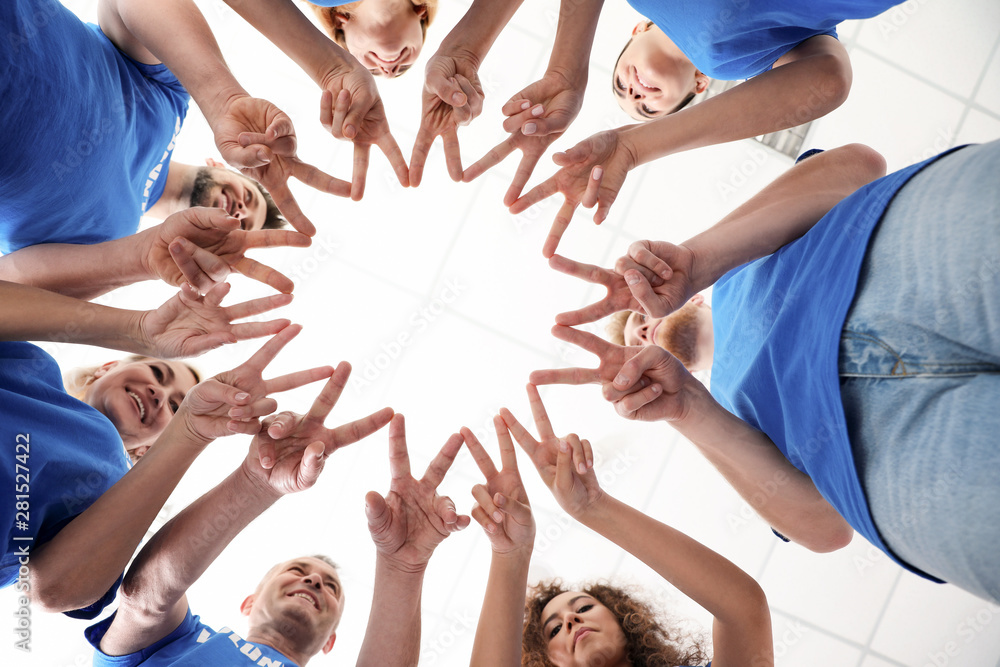 Team of volunteers putting their hands together on light background, bottom view Team of volunteers putting their hands together on light background, bottom view