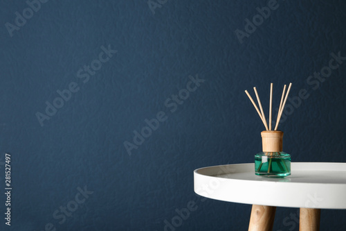Reed air freshener on table against dark blue background, space for text