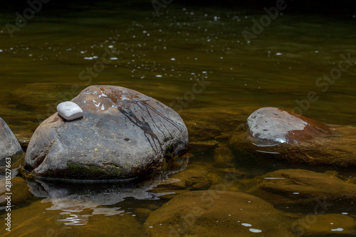 A bar of  white soap rests over a rock in a river at the temperate lands of the Andean mountains of central Colombia.