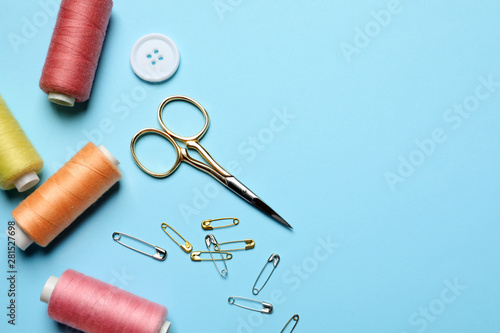 Flat lay composition with scissors and other sewing accessories on light blue background. Space for text