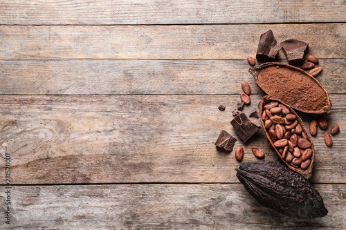 Flat lay composition with cocoa pods and beans on wooden table. Space for text