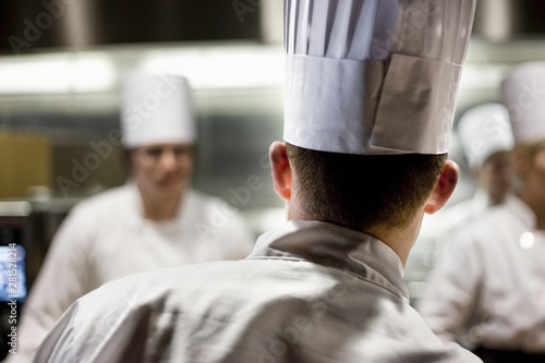 Rear view of chef wearing toque hat in commercial kitchen photo