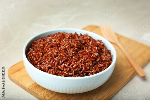 Bowl with delicious cooked brown rice on white table
