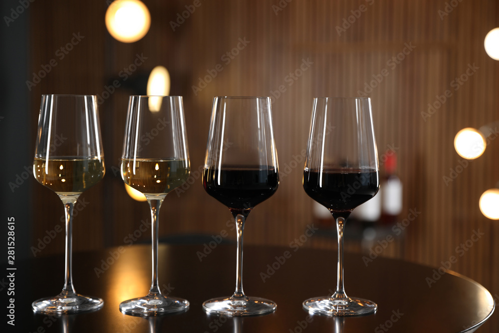 Glasses of different wines on table against blurred background