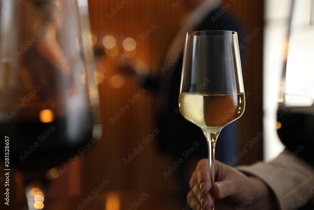 Woman with glass of wine in restaurant, closeup. Space for text