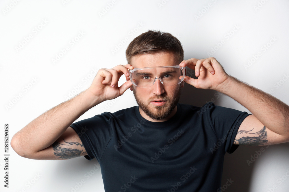 Young working man in protective glasses on light background Young working man in protective glasses on light background