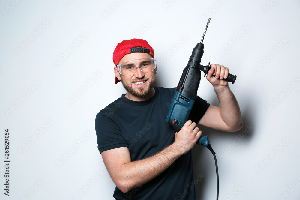 Young working man with rotary hammer on light background Young working man with rotary hammer on light background