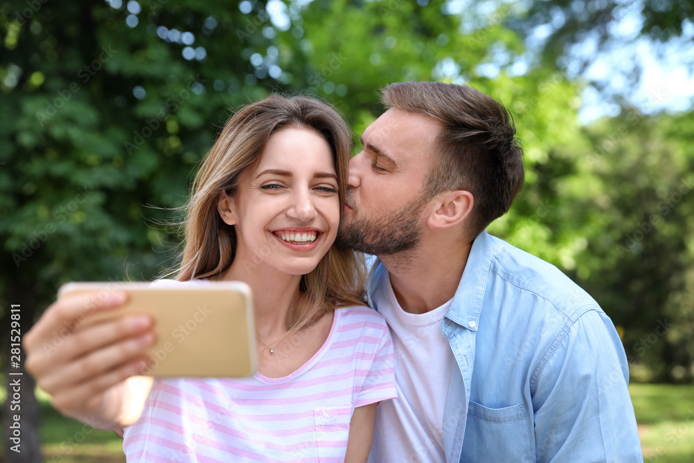 Happy young couple taking selfie in park