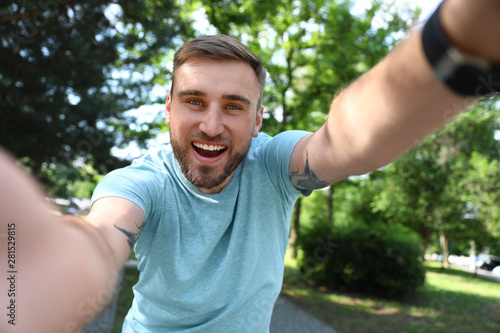 Happy young man taking selfie in park