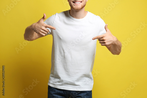 Young man wearing blank t-shirt on yellow background, closeup. Mockup for design