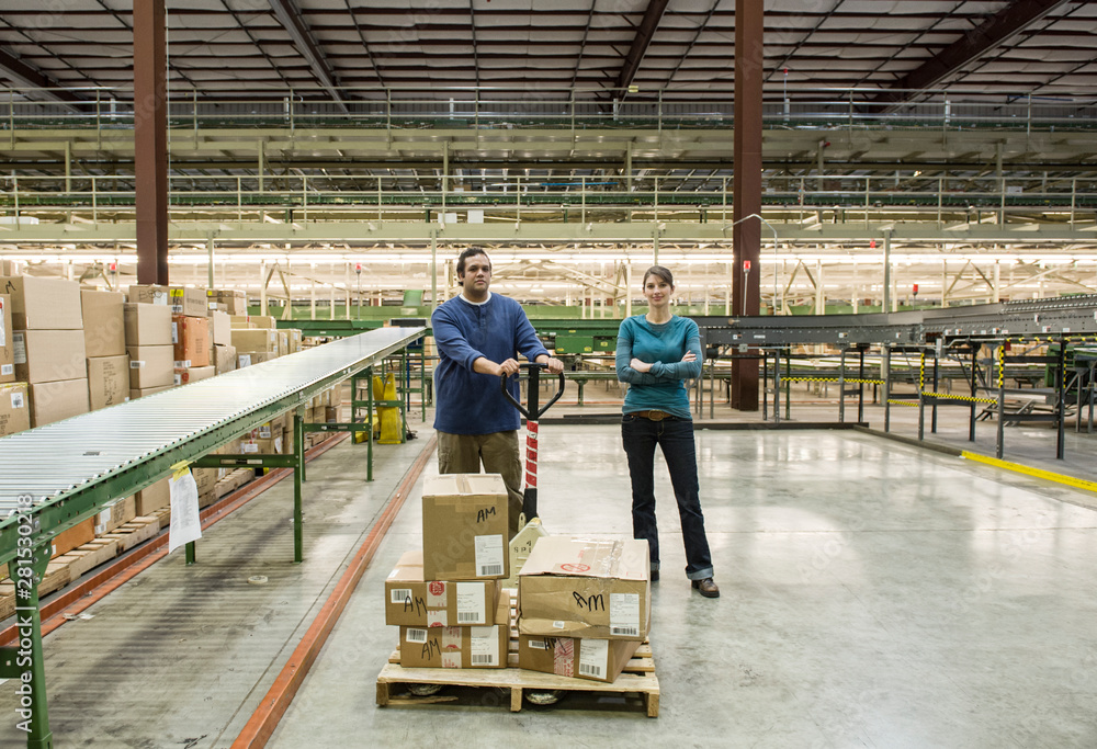 Portrait of workers with pallet jack standing in warehouse Portrait of workers with pallet jack standing in warehouse