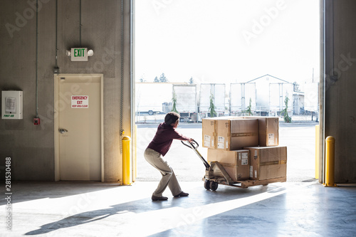 Worker using pallet jack in warehouse photo
