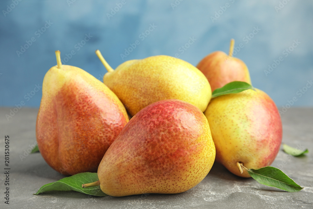 Heap of ripe juicy pears on grey stone table against blue background Heap of ripe juicy pears on grey stone table against blue background
