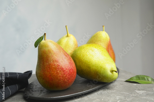 Ripe juicy pears on stone table against grey background