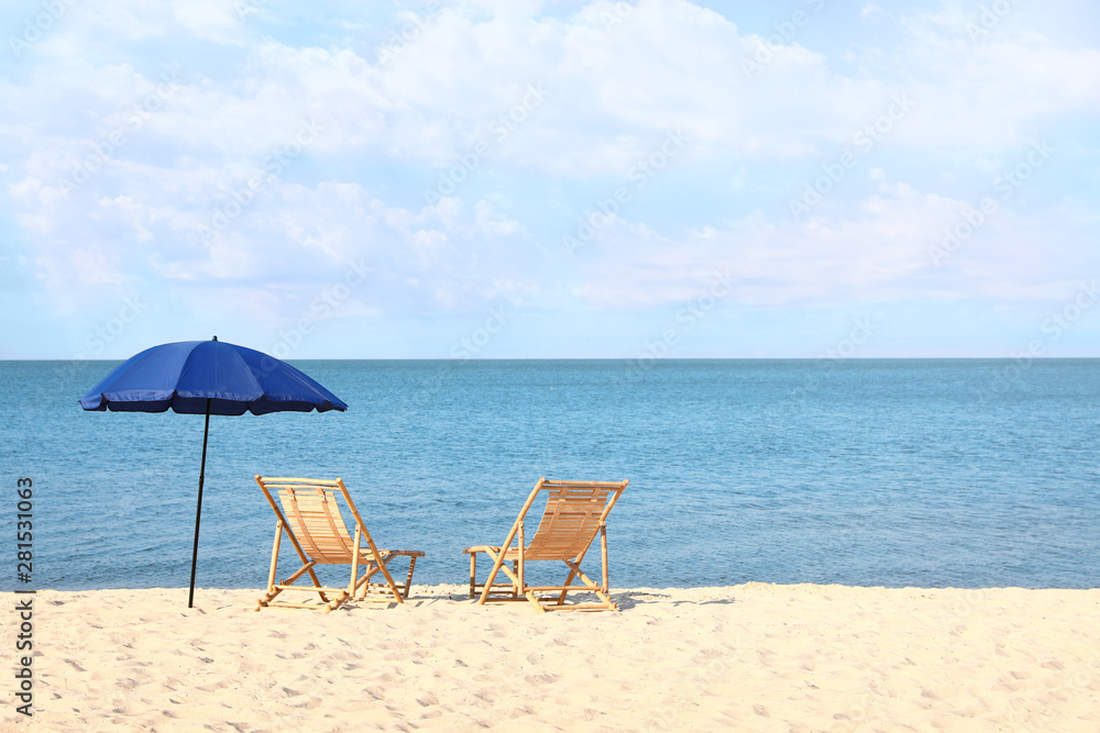Empty wooden sunbeds and umbrella on sandy shore. Beach accessories Empty wooden sunbeds and umbrella on sandy shore. Beach accessories
