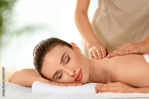 Beautiful young woman enjoying massage in spa salon