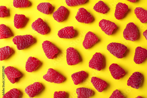Flat lay composition with delicious ripe raspberries on yellow background