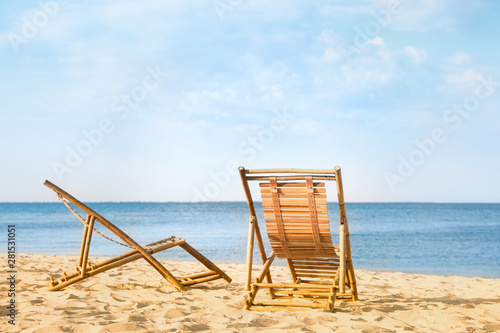 Sandy beach with empty wooden sunbeds on sunny day
