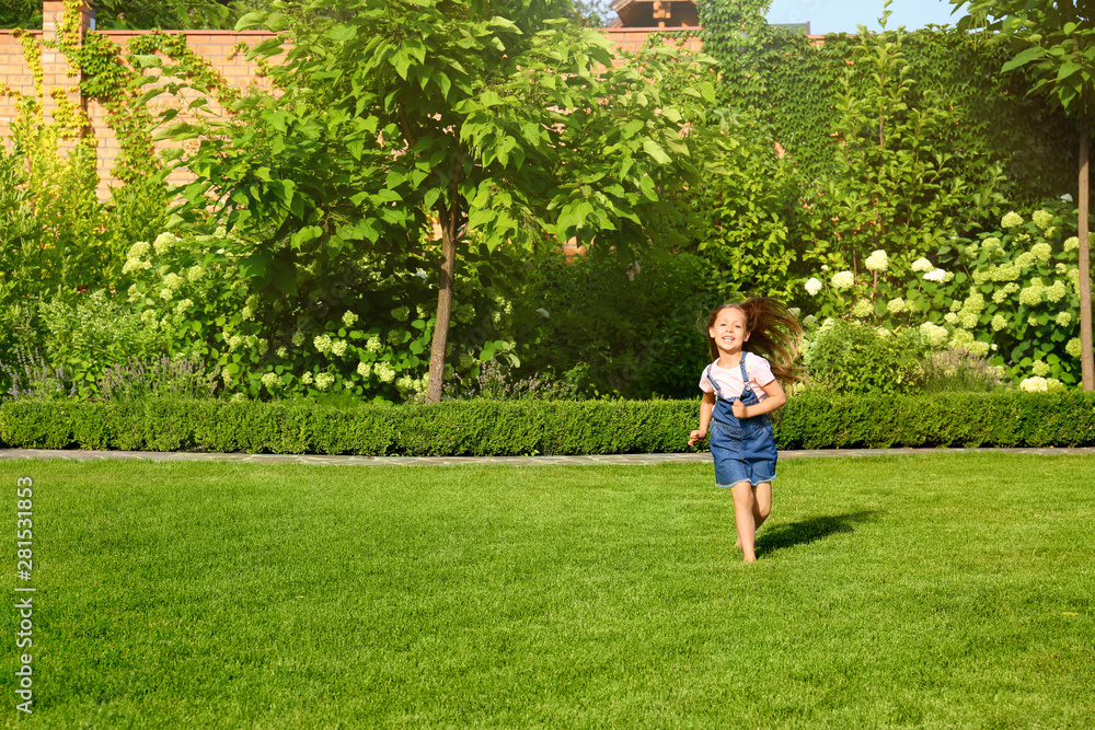 Cute little girl running in green park on summer day