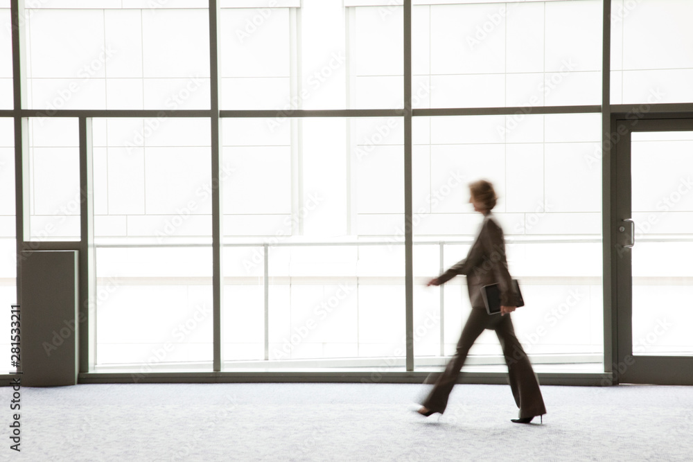 Side view of businesswoman passing by window of convention center Side view of businesswoman passing by window of convention center