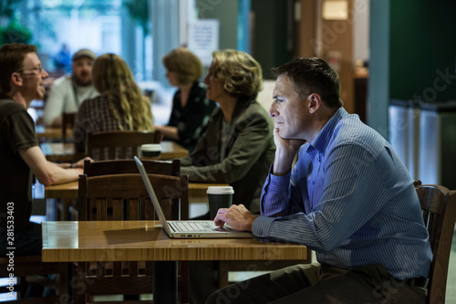 Side view of businessman working on laptop in cafe photo