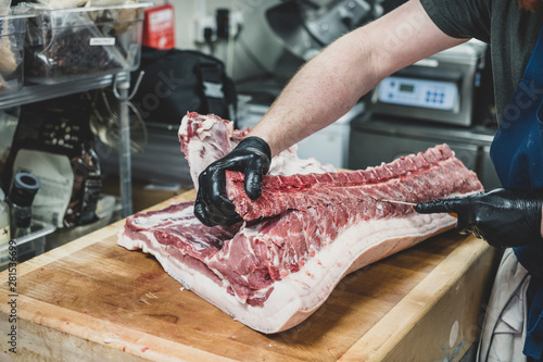 Midsection of man cutting pork ribs on butcher's block photo