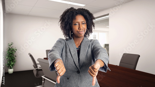 Black African American businesswoman in an office with thumbs down.  She is an owner or an executive of the workplace.  Depicts careers and startup business. photo