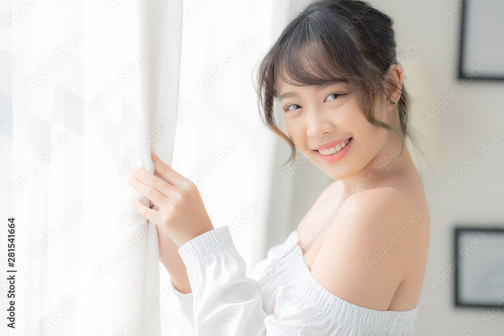 Portrait of beautiful young asian woman standing the window and smile while wake up with sunrise at morning, girl happy with freshness and cheerful, lifestyle and relax concept. Portrait of beautiful young asian woman standing the window and smile while wake up with sunrise at morning, girl happy with freshness and cheerful, lifestyle and relax concept.