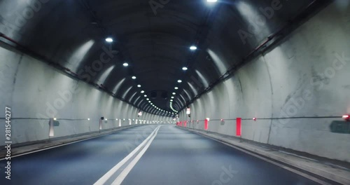 Driving along the modern illumanated empty tunnel on freeway to the big city at night. No people. Night adventure roadtrip.