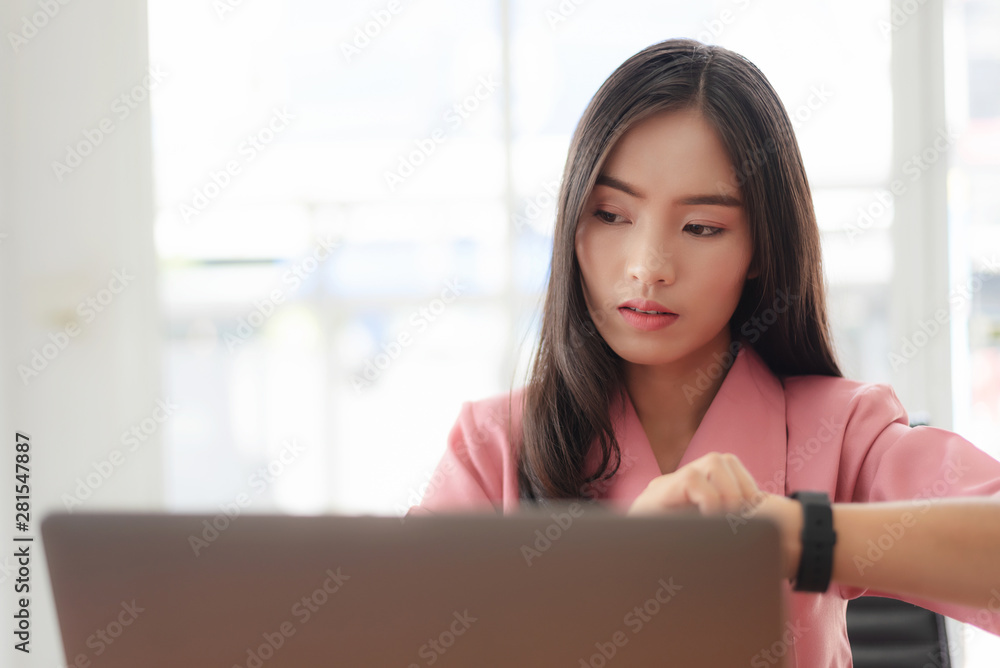 Young asian businesswoman checking the time, work with laptop computer. Young asian businesswoman checking the time, work with laptop computer.