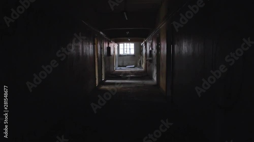A long and dark corridor with a window at the end in an abandoned factory photo