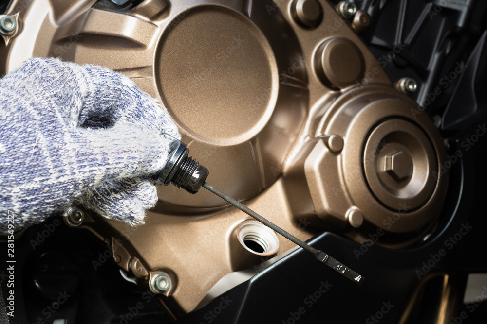 Hand of technician wearing cloth gloves check lubricant engine oil