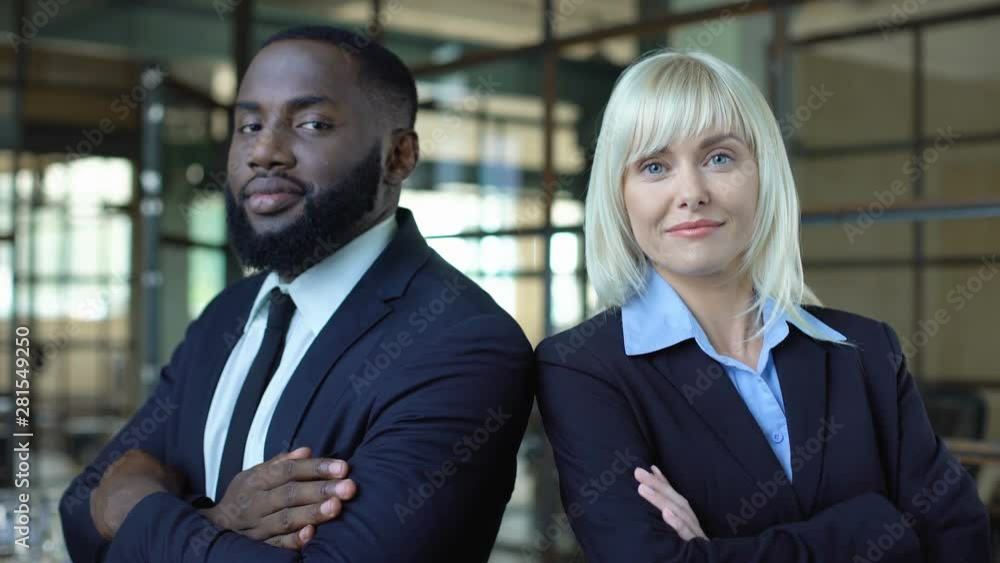 African man and caucasian woman in suits folding arms, professional managers African man and caucasian woman in suits folding arms, professional managers