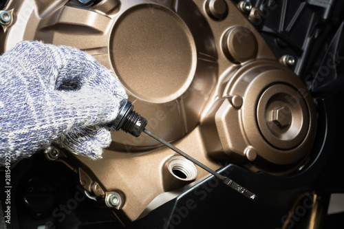Hand of technician wearing cloth gloves check lubricant engine oil level motorcycle bigbike. maintenance motorcycle concept in garage or check before you travel.