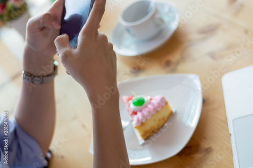 woman taking picture of strawbery cake with smartphone