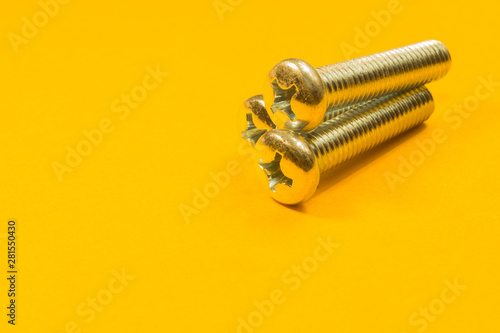 Screws on a yellow background. pile of fasteners