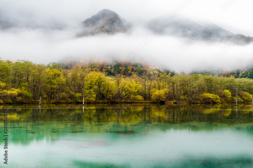 Lake Taisho in Kamikochi national park with misty in morning time, water reflection. the lake is located in the Hida Mountains, the Northern Alps of the Japanese Alps in Japan. 