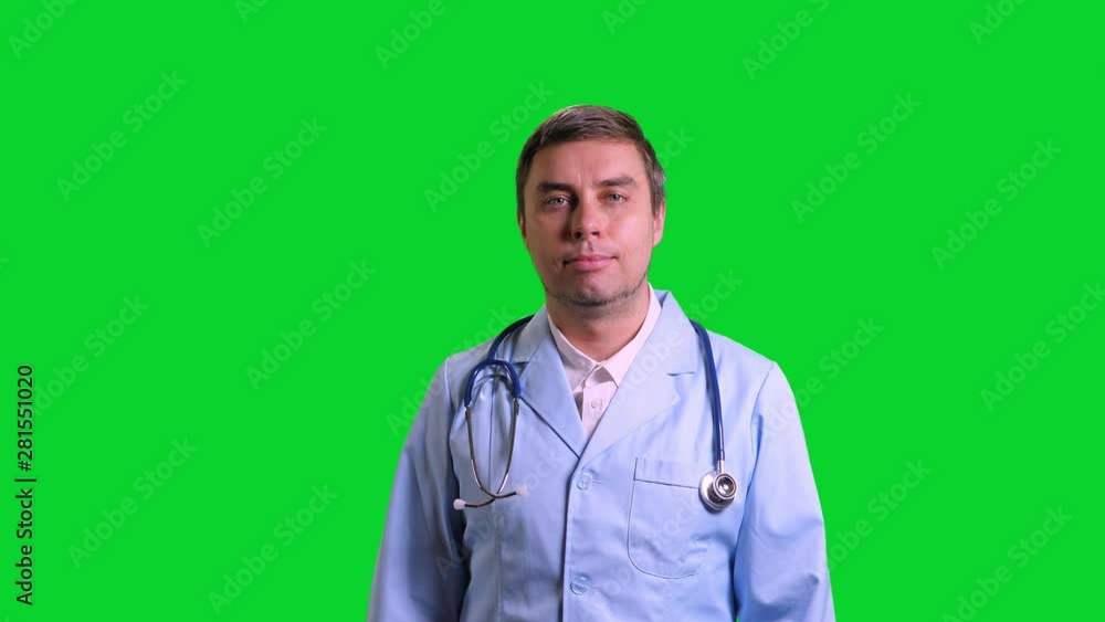 Young doctor stand and smile. Man in blue medical uniform with stethoscope on green chroma key background Young doctor stand and smile. Man in blue medical uniform with stethoscope on green chroma key background