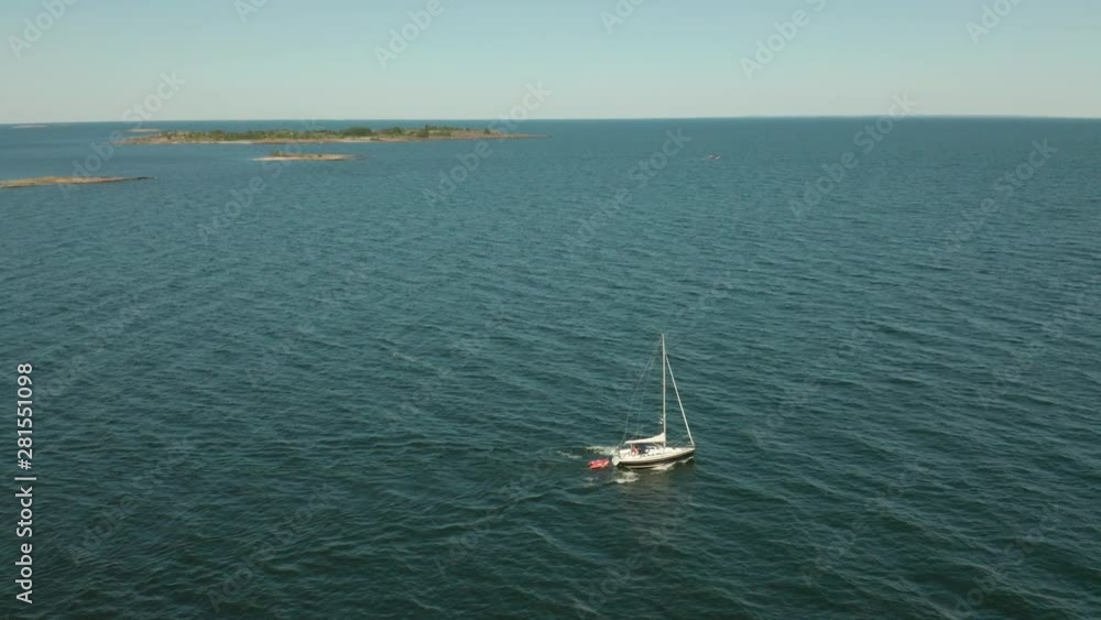 Sailboat sailing on calm blue sea archipelago. Cliffs & horizon background. Panning aerial shot. Sailboat sailing on calm blue sea archipelago. Cliffs & horizon background. Panning aerial shot.
